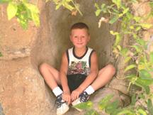 Kyle sitting in shady niche of large boulder